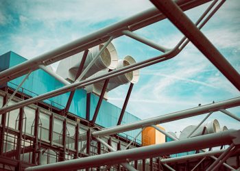 low-angle photography of building with large white pipes on roof