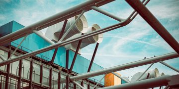 low-angle photography of building with large white pipes on roof