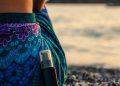 black bottle leaning on woman sitting on rocky shore during day
