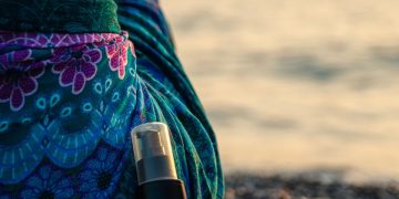 black bottle leaning on woman sitting on rocky shore during day
