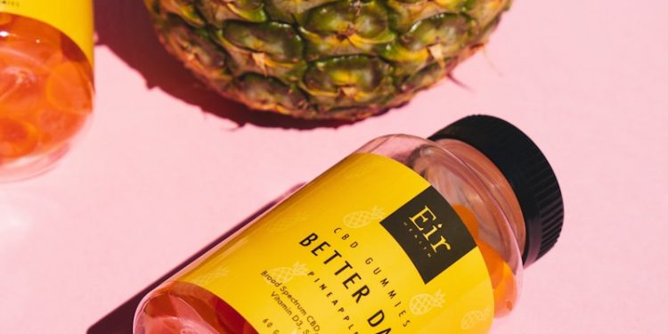 a pineapple next to a pineapple and a bottle of body lotion