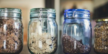 four glass jars filled with different types of food