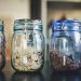four glass jars filled with different types of food