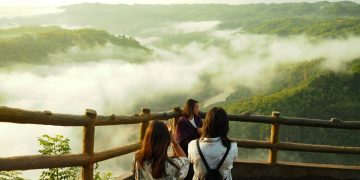 three woman standing on mountain cliff