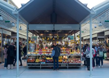 a person standing in front of a fruit stand