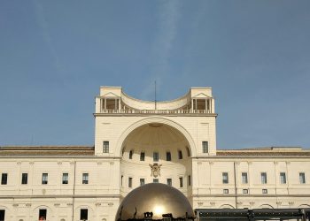 a large white building with a large metal ball in front of it