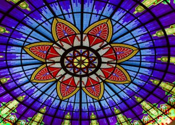 A colorful stained glass ceiling with a flower design