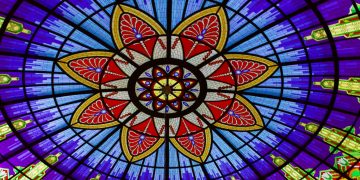 A colorful stained glass ceiling with a flower design