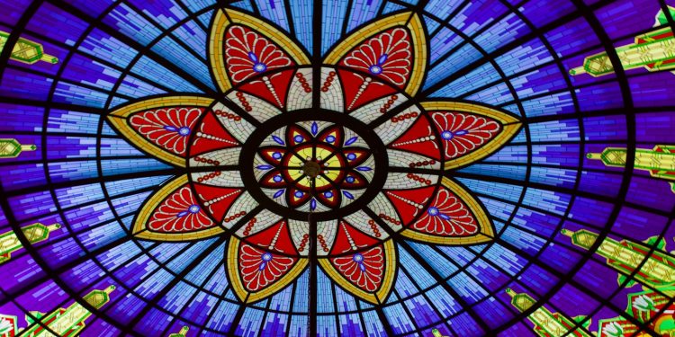 A colorful stained glass ceiling with a flower design