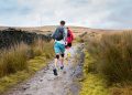 man in blue jacket walking on dirt road during daytime