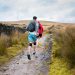 man in blue jacket walking on dirt road during daytime
