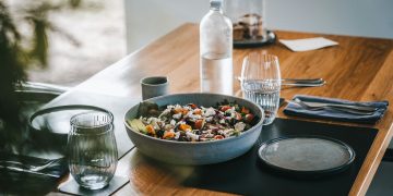 a wooden table topped with a bowl of food