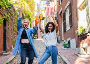 2 women standing on brown brick floor during daytime