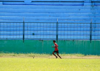 a young man running across a lush green field