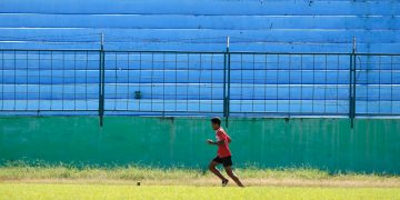 a young man running across a lush green field