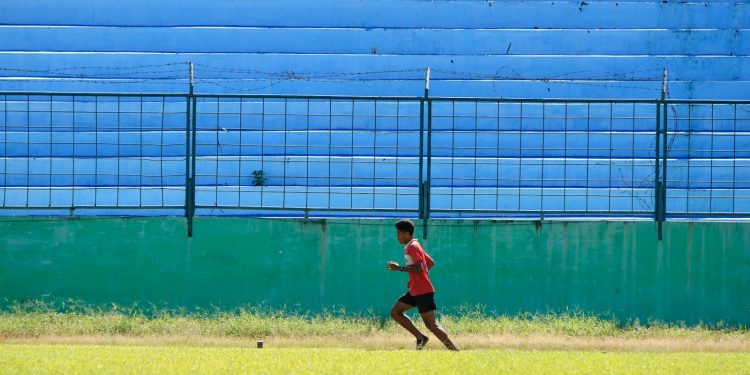 a young man running across a lush green field