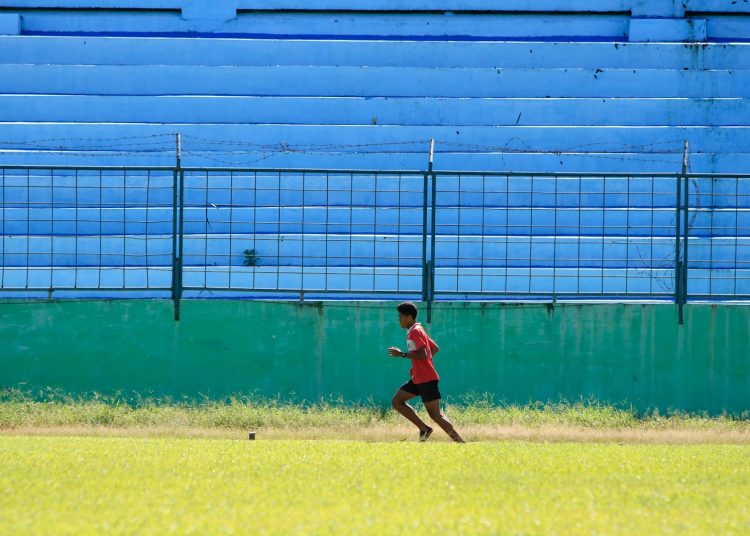 a young man running across a lush green field